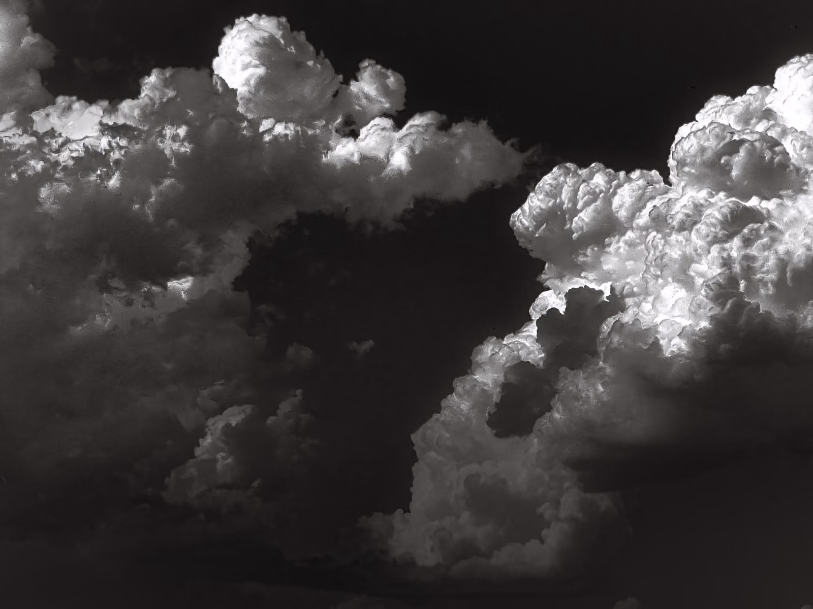 Nuvole temporalesche imponenti, in bianco e nero, con forte contrasto tra luce e ombra.